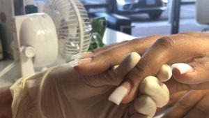 An image of a person receiving dip powder nails.