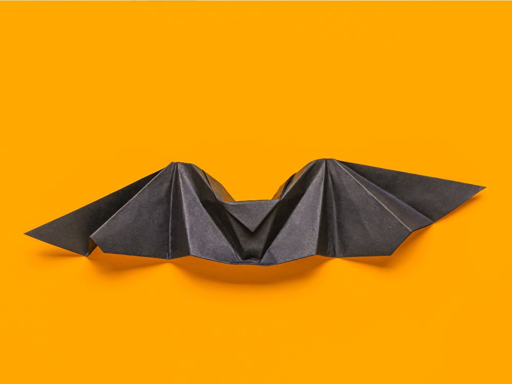 an image of an origami bat with a yellow background.
