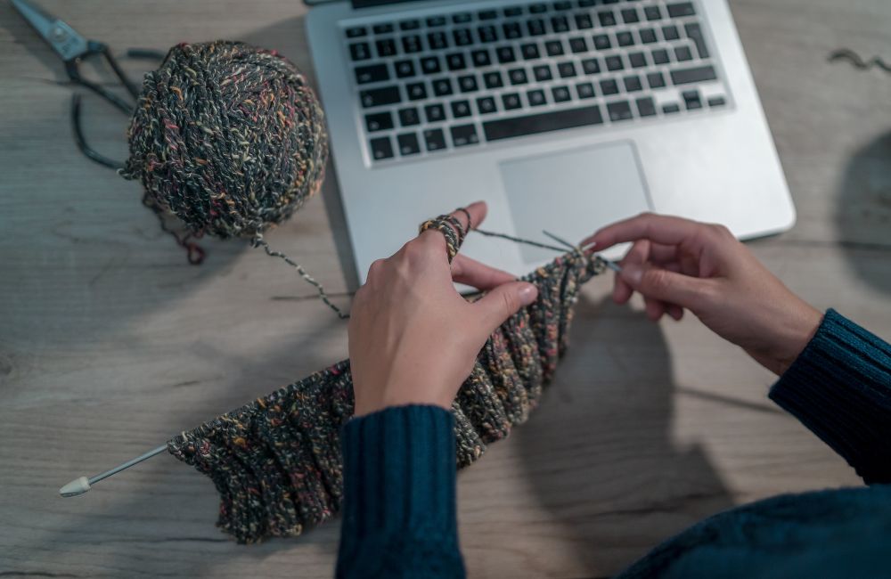 An image of a woman following an online tutorial to knitting.