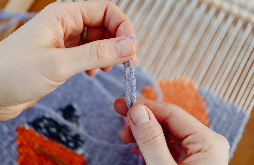 An image of a woman picking a fiber for knitting.