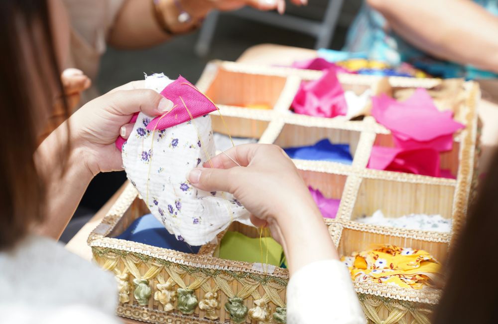 An image of a person hand sewing fabrics for a craft project.