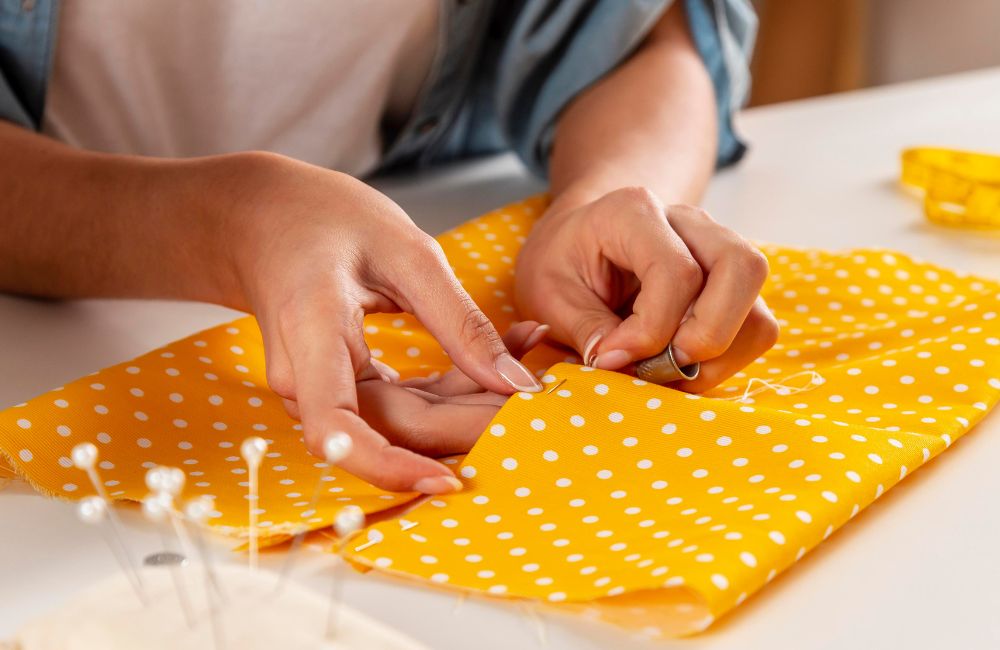 An image of a person hand sewing fabrics for a garment.