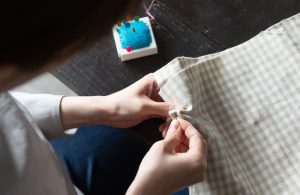 An image of a person hand sewing fabric.