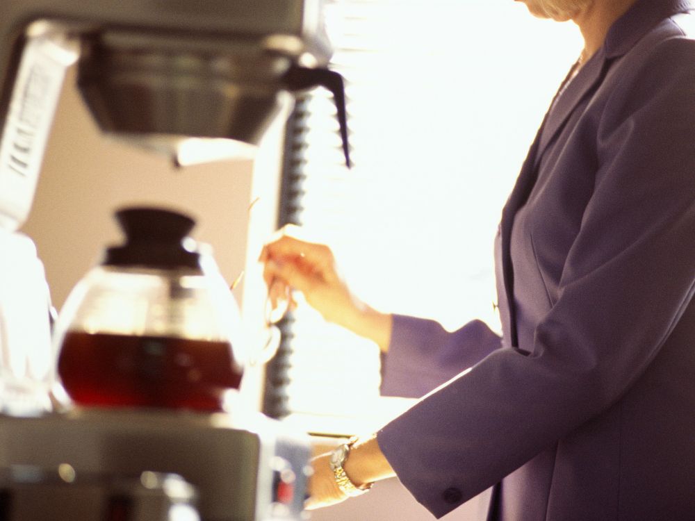 An image of a woman fixing a cup of coffee.