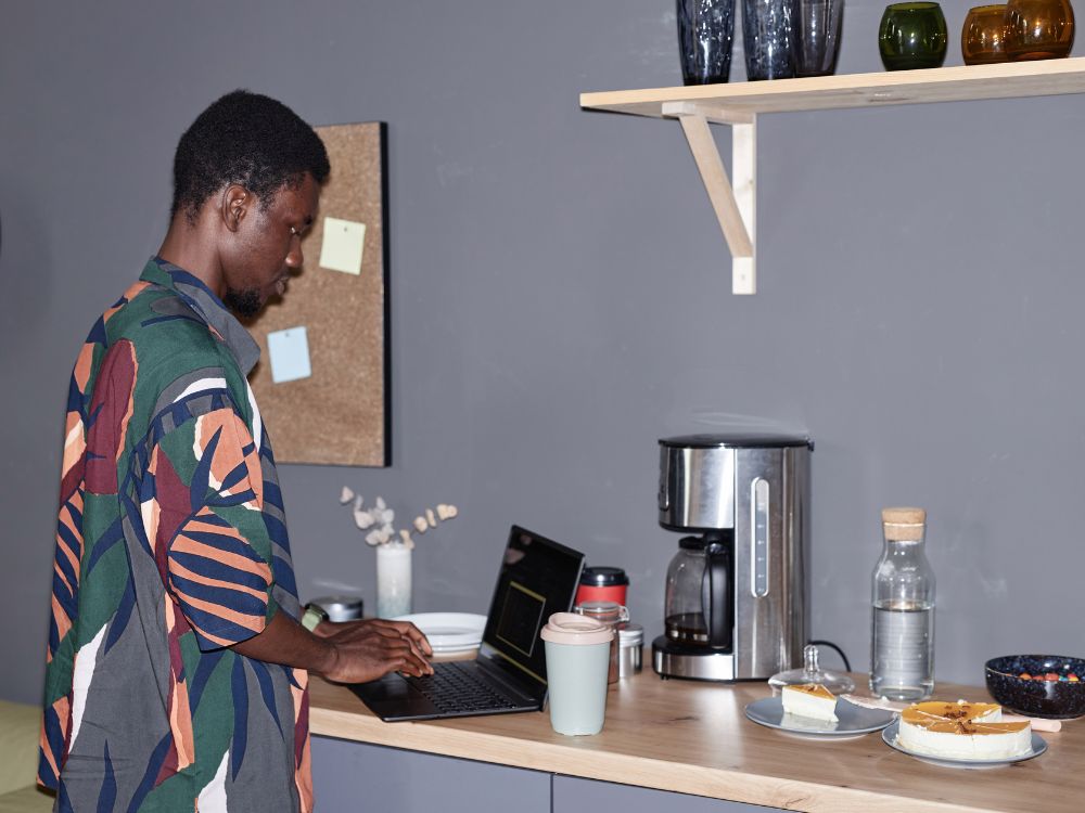 An image of a man using a laptop on a coffee station. 