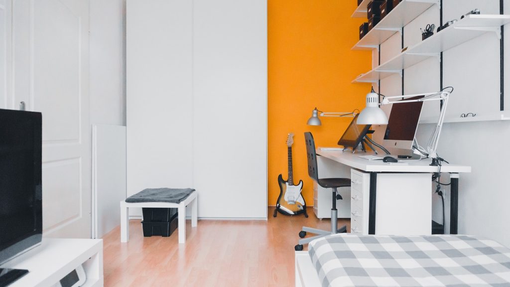 A bedroom with an orange accent wall