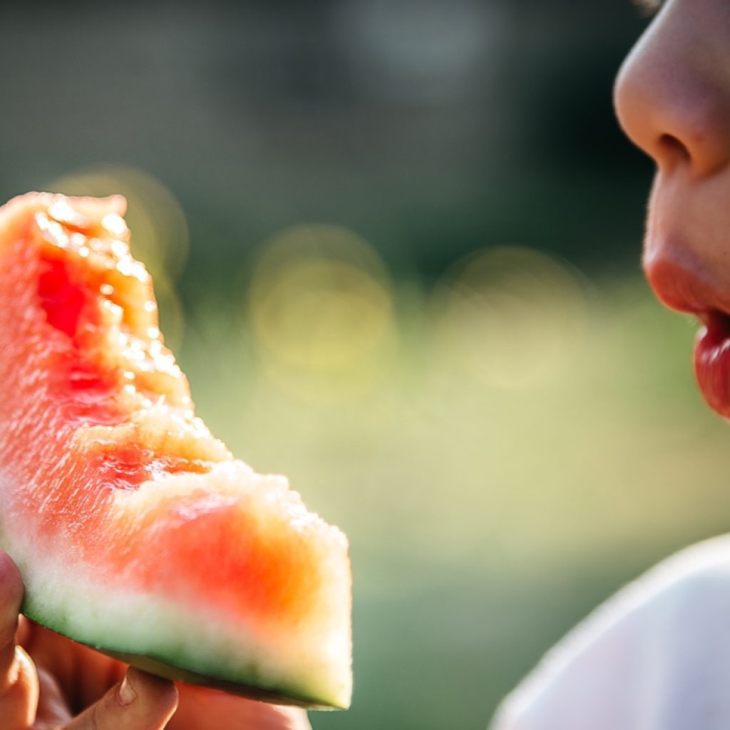 A young boy eating a slice of watermelon.
